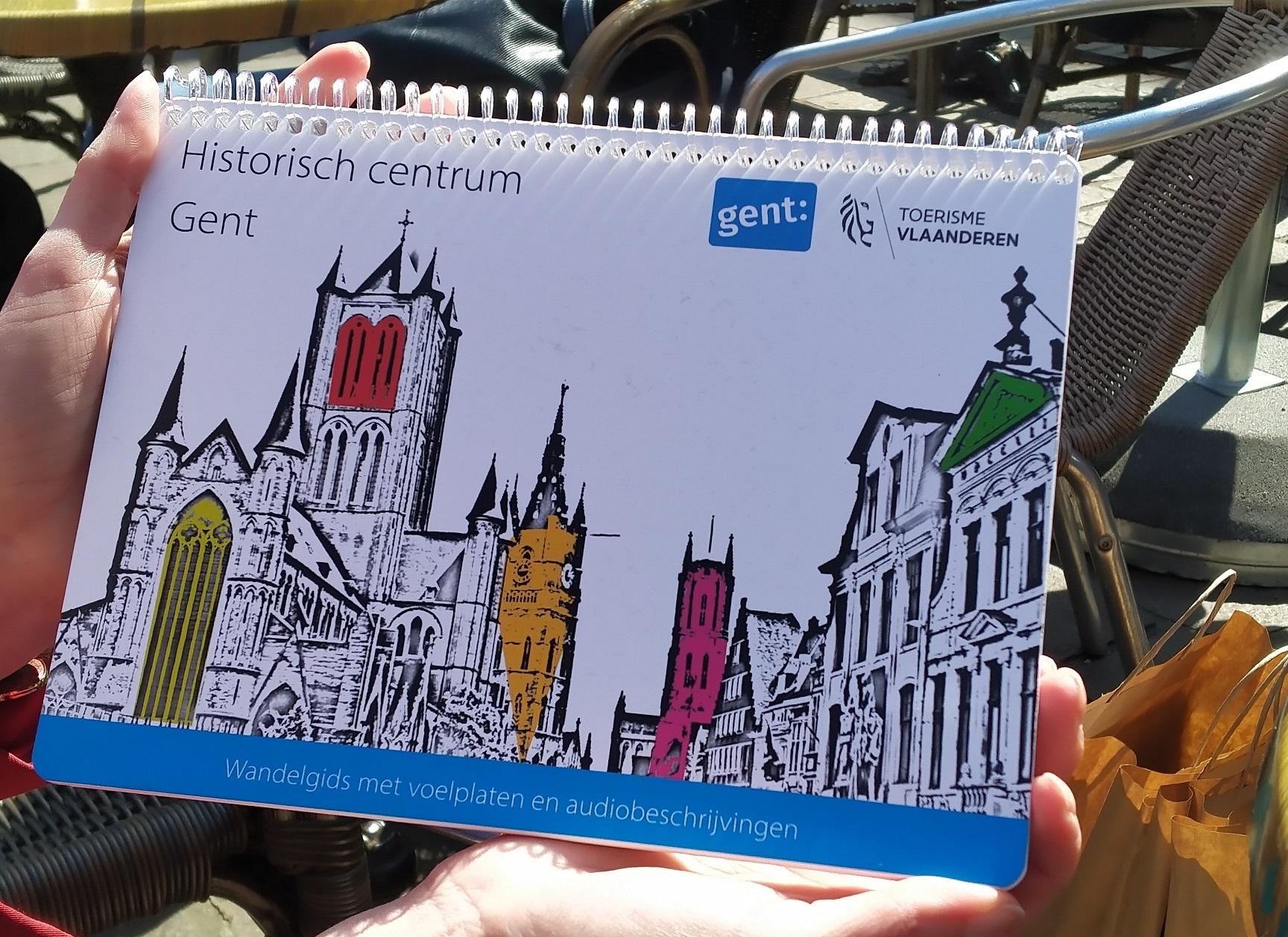 De voorkant van de wandelgids met een afbeelding van de drie torens en de tekst: Historisch centrum Gent - wandelgids met voelplaten en audiobeschrijvingen