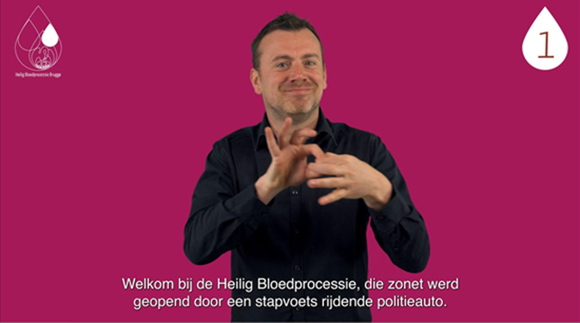 Een beeld uit de videogids bij de Heilig Bloedprocessie met een tolk Vlaamse gebarentaal en ondertiteling.